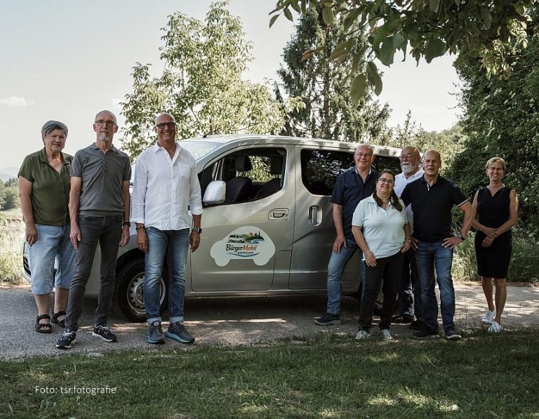 Team BürgerMobil Gruppe von acht Personen neben dem BürgerMobil Van in einem grünen Außenbereich.